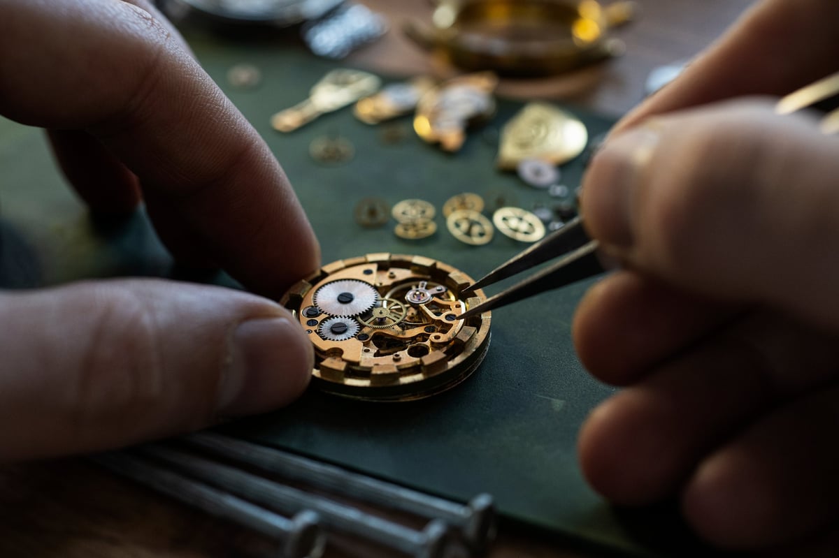 Watchmaker repairing mechanical watch movement with precision tools